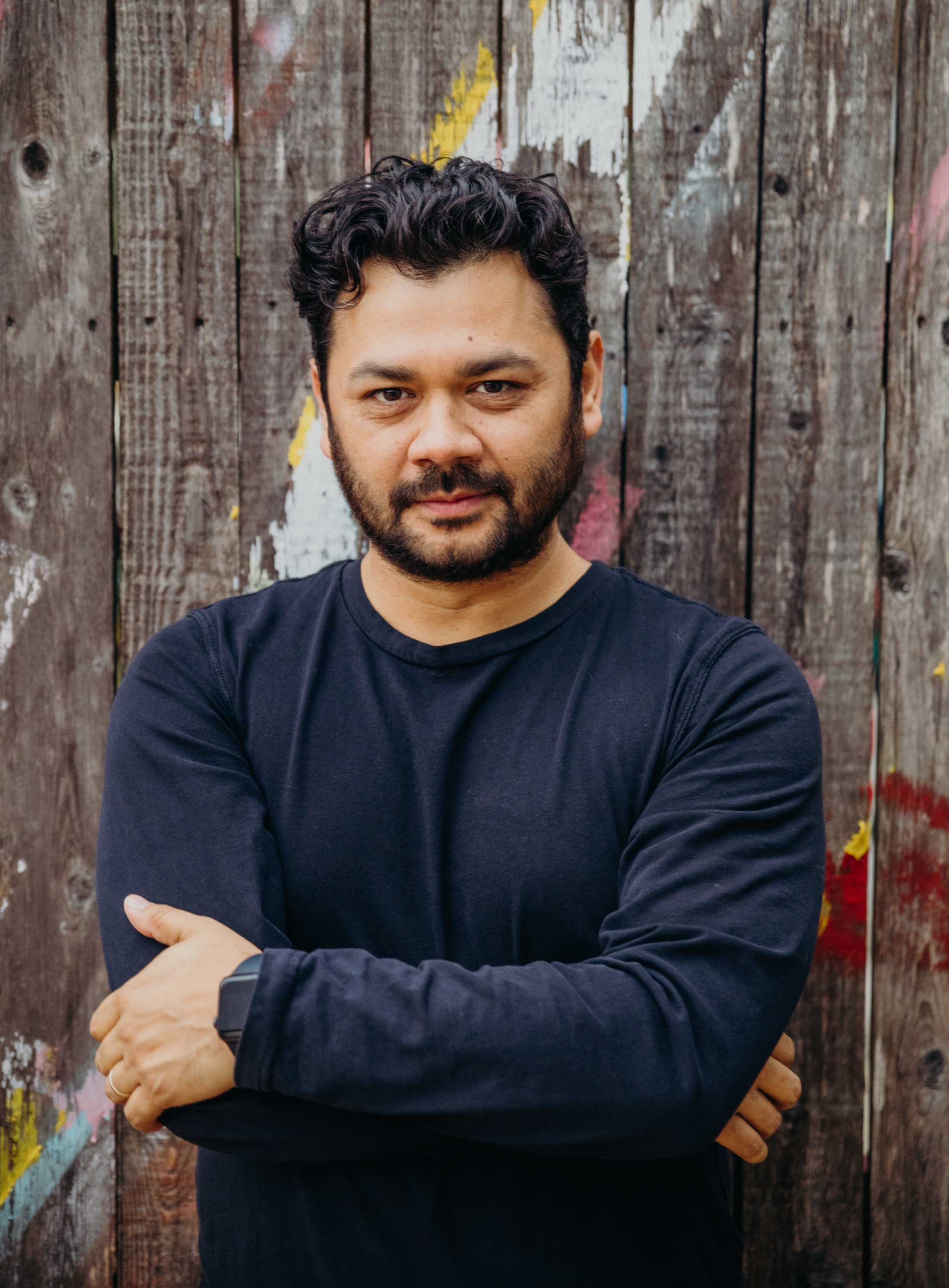 Photo of Gabriel Solis against a wooden fence.