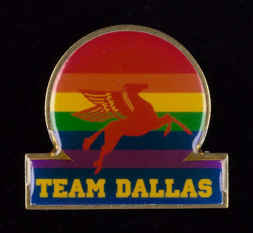 Photo of a pin from the digitization project with rainbow background, red pegasus and yellow Team Dallas text.